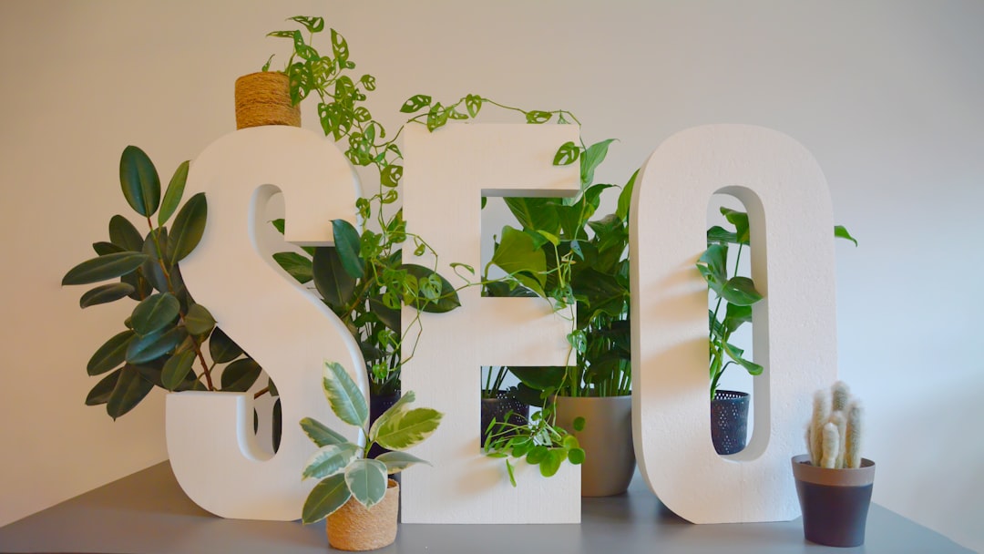 Vibrant and nature-inspired office setting at an SEO agency, featuring large SEO letters prominently displayed on a modern desk. The letters are adorned with an abundance of lush green plants, creating a refreshing and natural atmosphere. The combination of digital focus and greenery brings a unique balance of productivity and tranquility to the workspace.